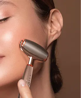 Close-up of a woman using a rose gold facial massage roller on her cheek for skincare and face lifting.