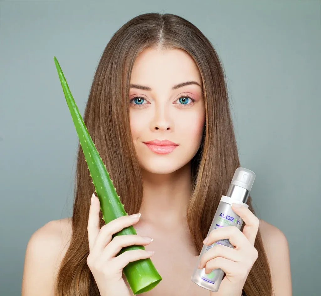 Lifestyle skincare marketing featuring 3d rendering of an Aloeksyl spray bottle held by a model next to an aloe vera leaf.