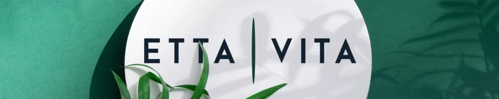 Etta Vita Amazon storefront header design featuring a minimalist logo on a white circular podium with green botanical shadows.