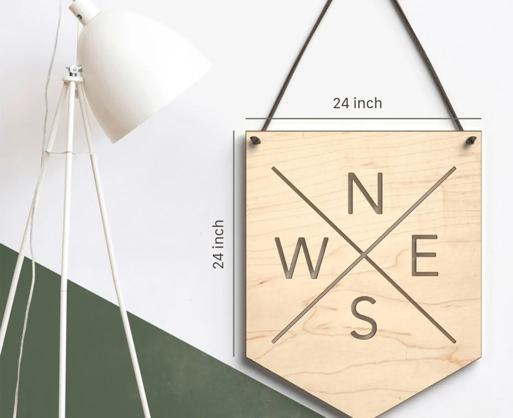Infographic-style 3D product rendering of a wooden compass wall board showing 24-inch height and width dimensions against a minimalist wall.