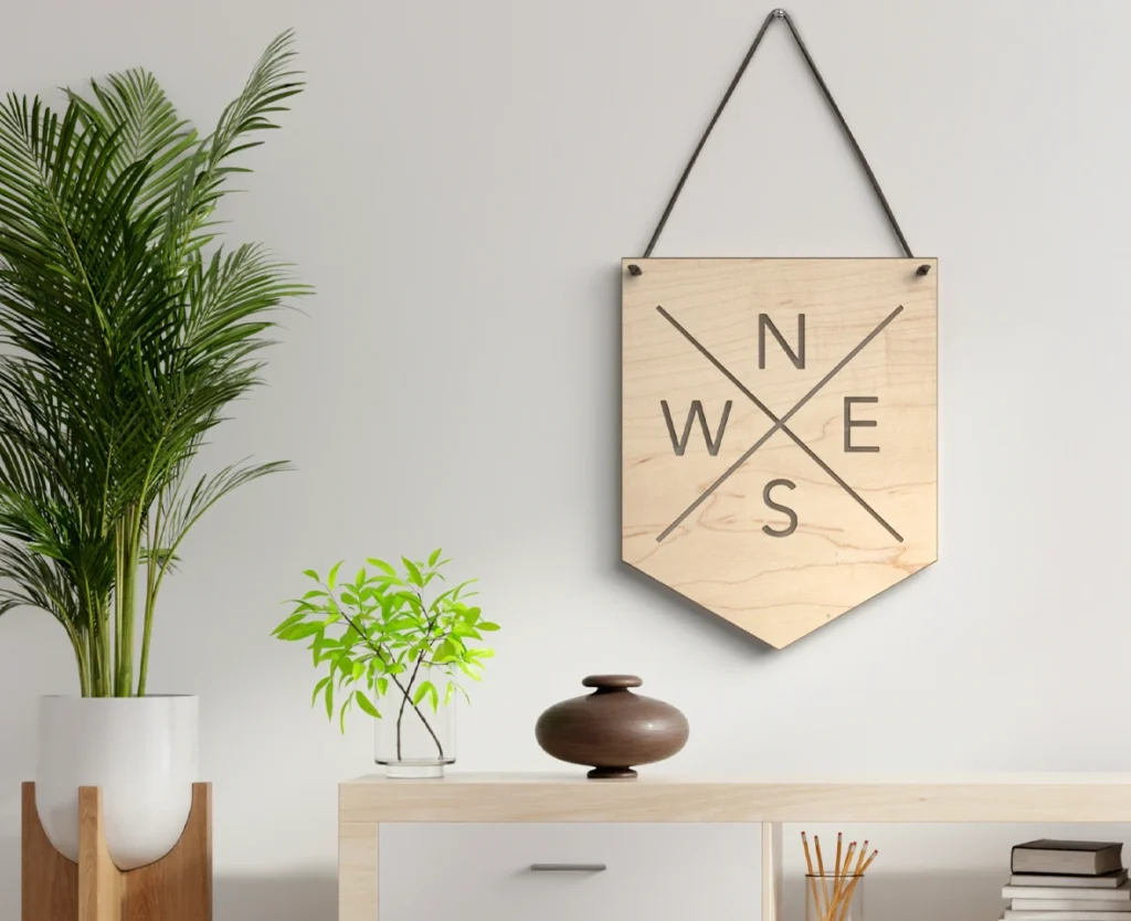 3D lifestyle product rendering of a wooden compass wall decor hanging above a modern console table with indoor plants and minimalist home accessories.